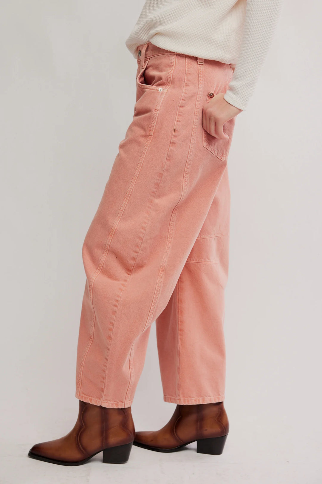 A person wearing wide-leg dusty pink corduroy pants with brown ankle boots and a cream top, shown from the waist down against a light gray studio background.
