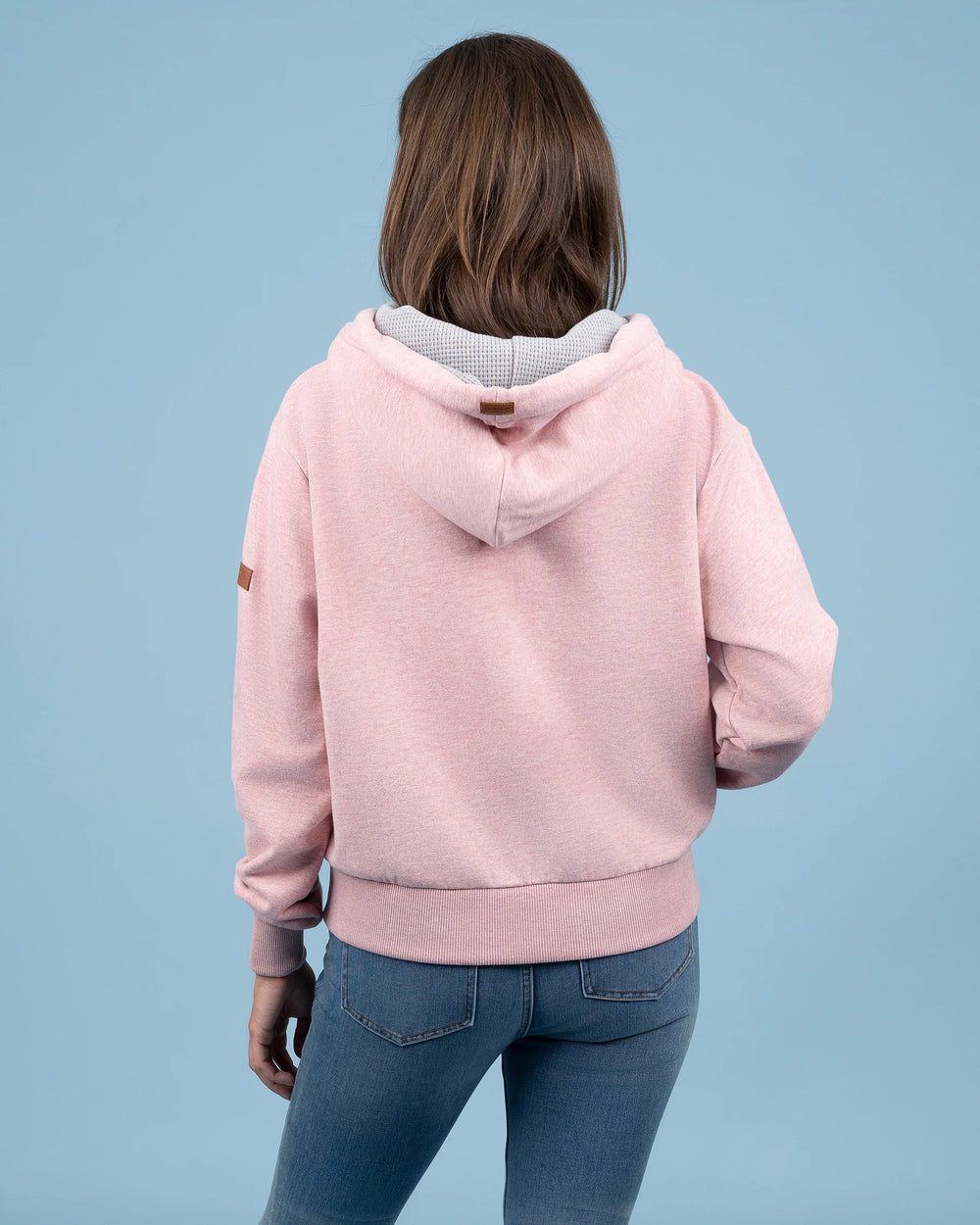 Person wearing a pink hoodie with a plain background