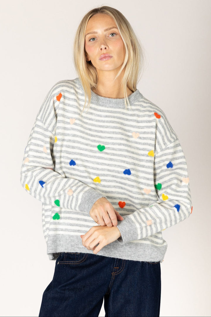 Woman wearing a gray striped sweater with colorful polka dots on a plain background