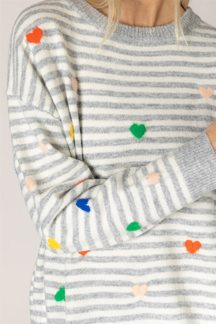 Gray and white striped sweater with colorful heart patterns on a light gray background