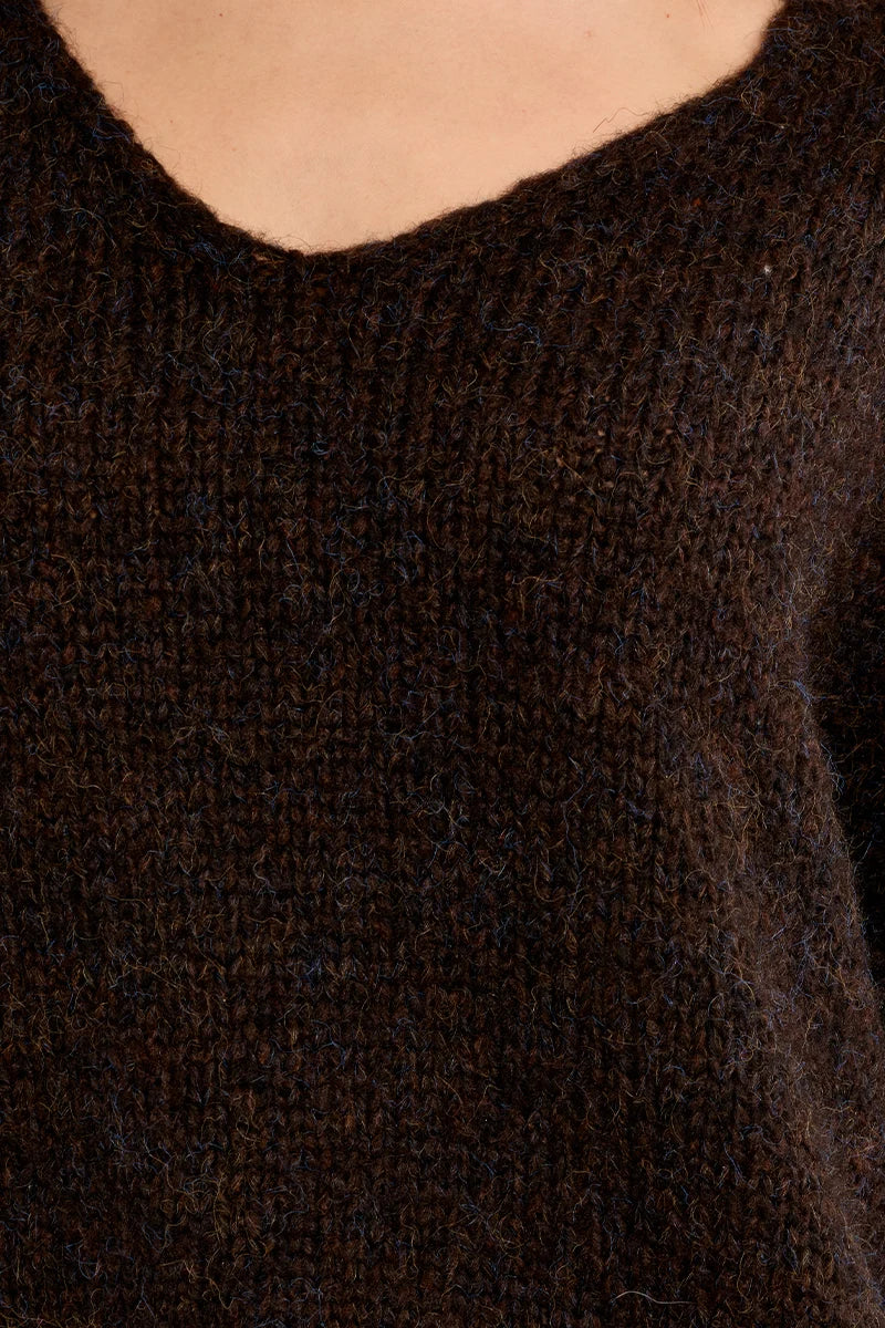 Close-up of a dark brown knit sweater with a V-neck, worn by a model.