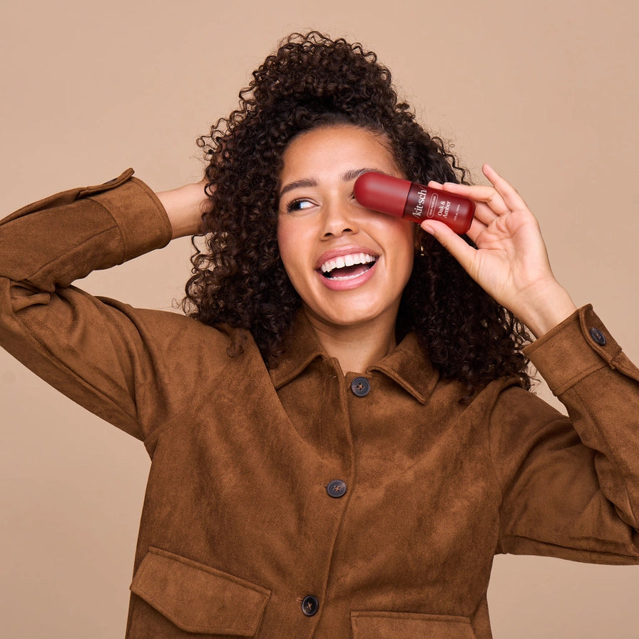 Woman holding a red lipstick against her face on a beige background