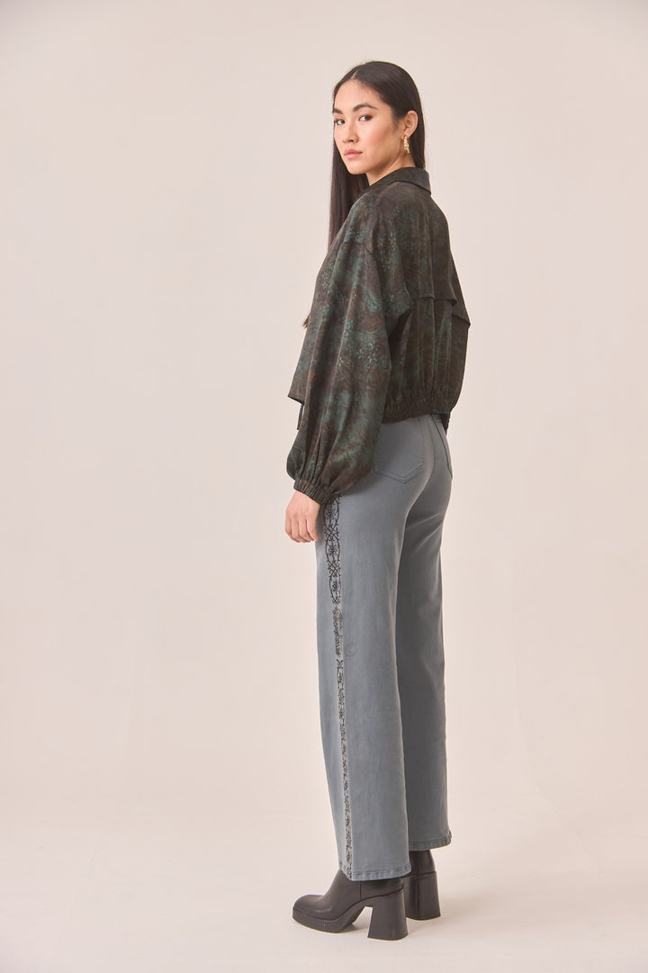 Woman wearing a patterned shirt and jeans on a beige background