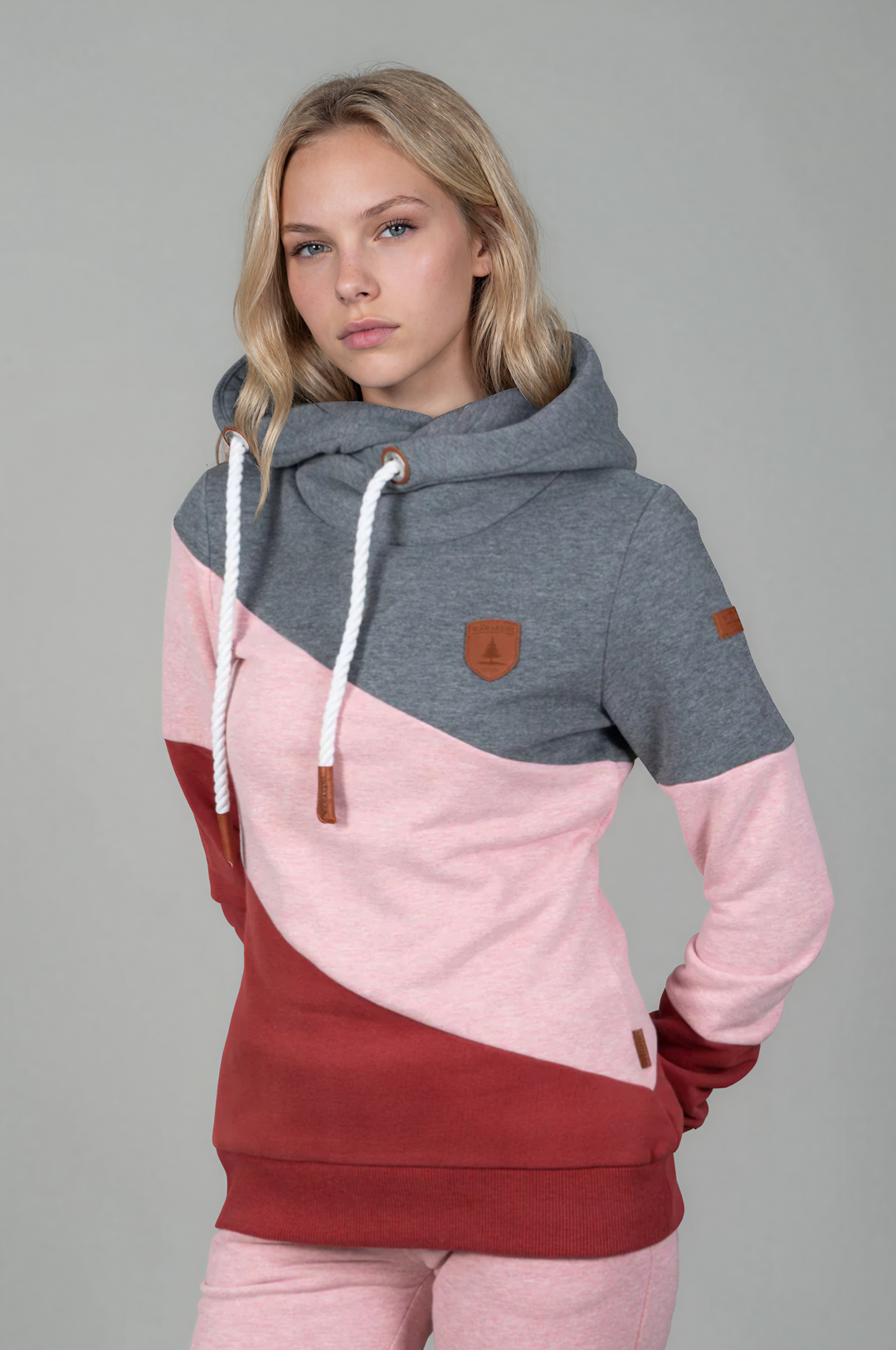 Woman wearing a color-blocked hoodie and pants on a gray background