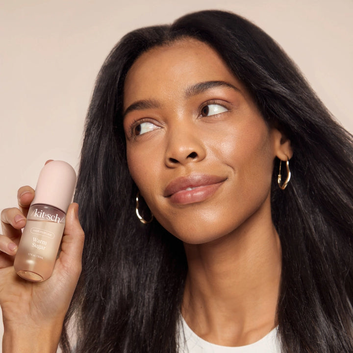Woman holding a makeup product with a neutral background